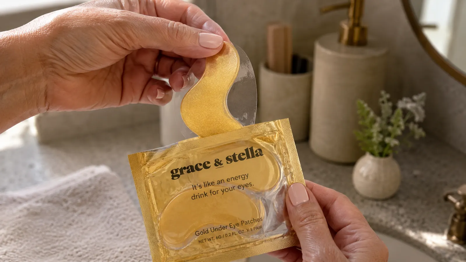 Hand peeling a gold hydrogel eye patch out of its packaging